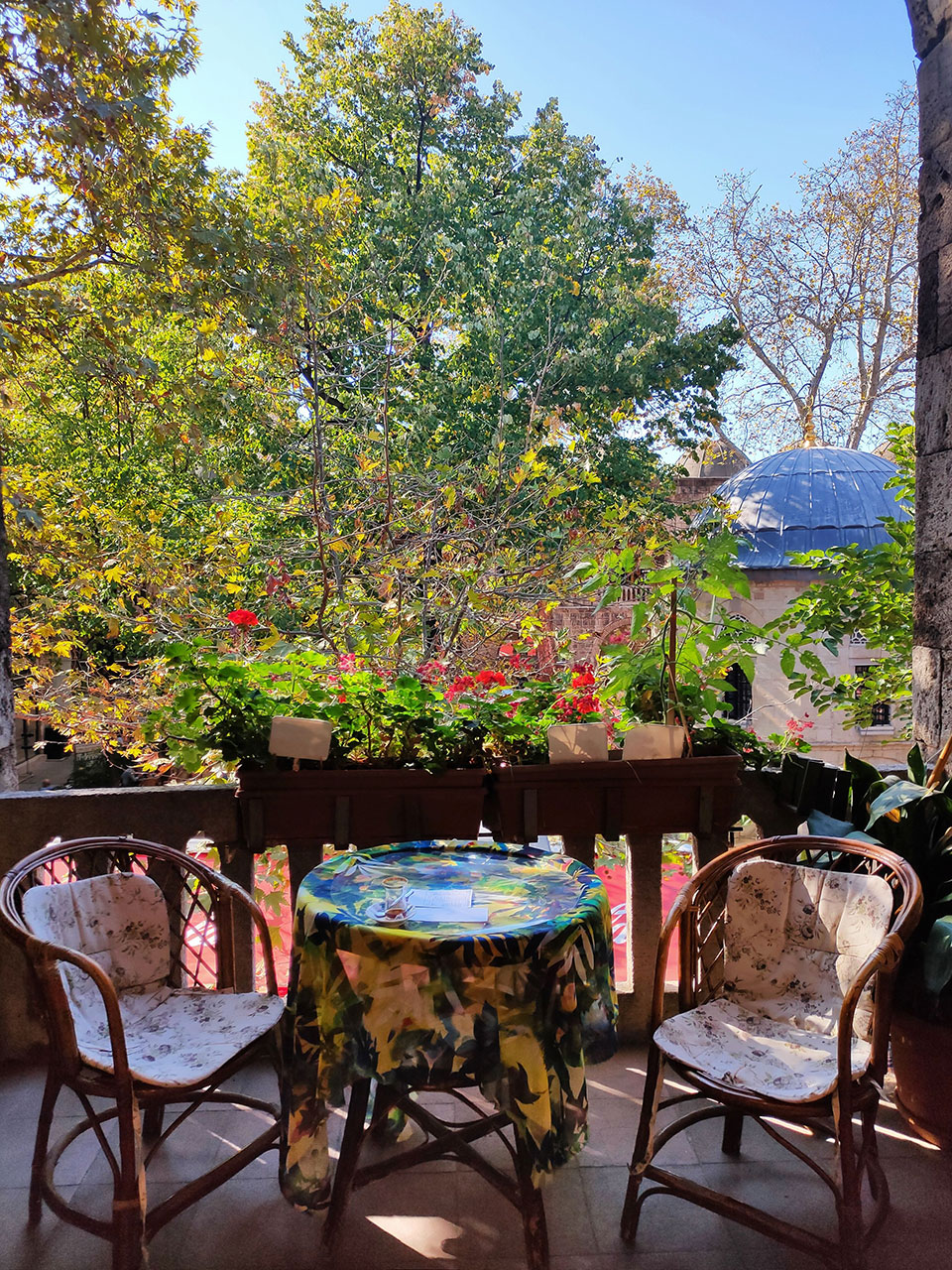 słoneczny balkon ze stolikiem, fotelami i kwiatami przy balustradzie