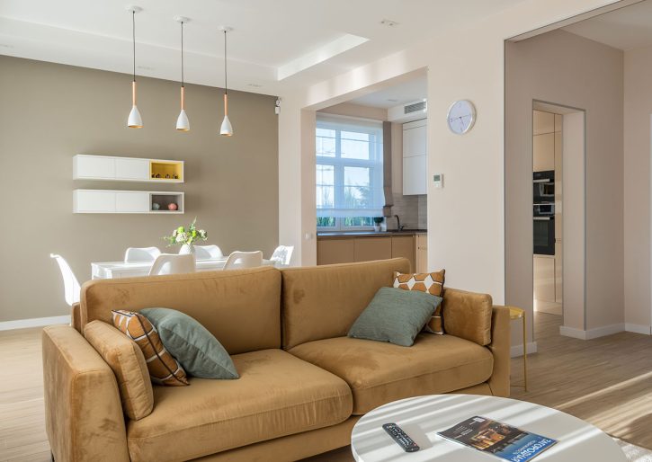 brązowa sofa w beżowym salonie z zielonymi dodatkami