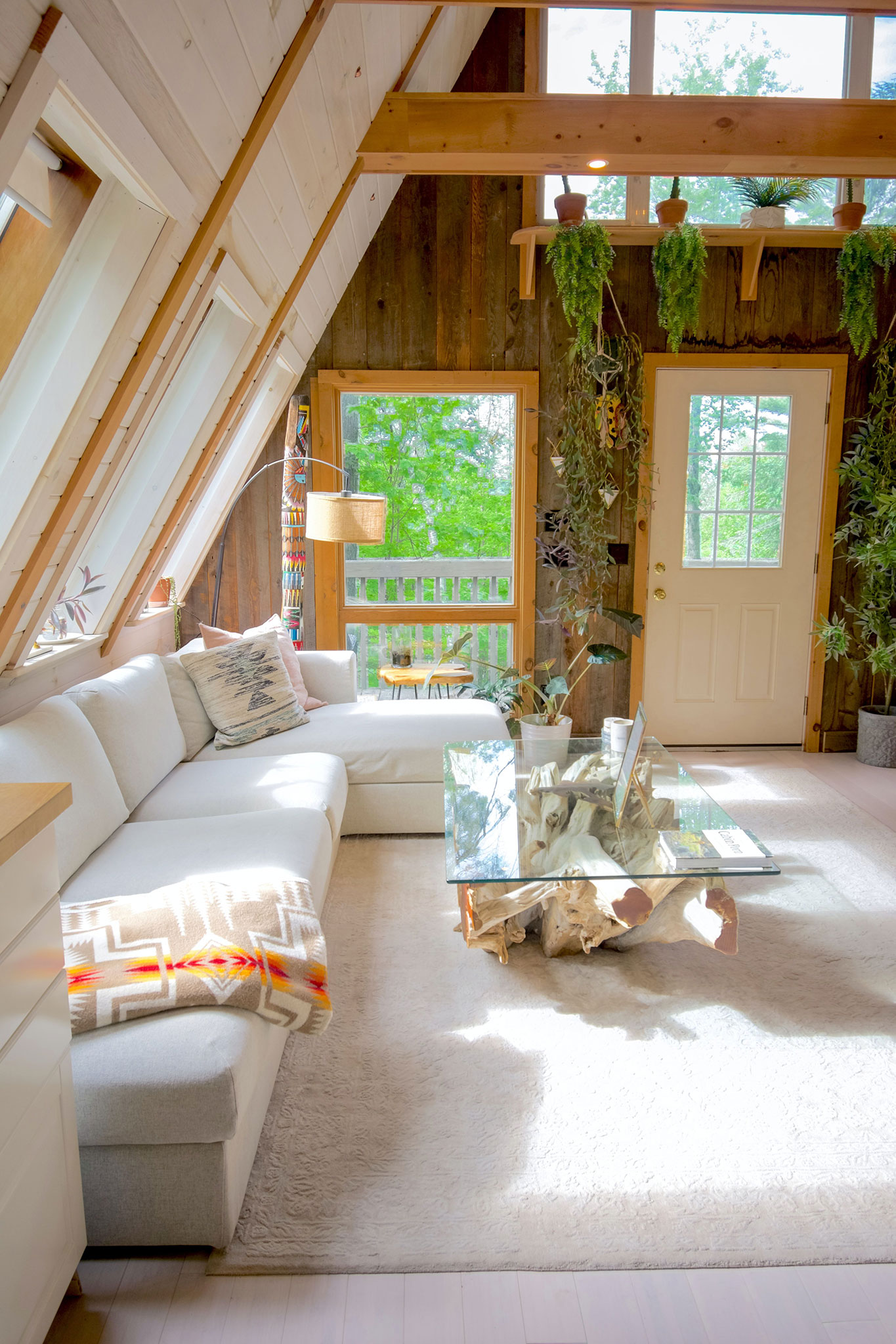 jasny salon scandi boho z drewnem roślinami i białą sofą