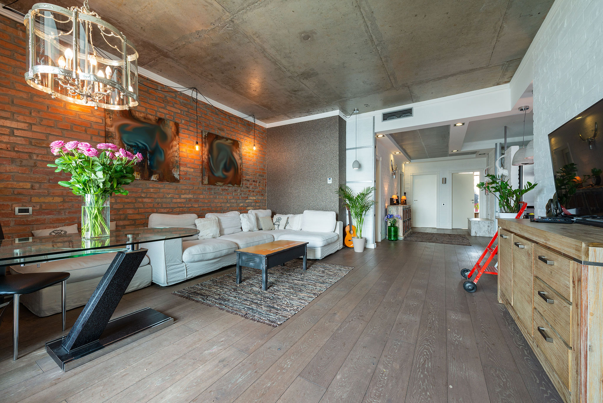 Duży salon loftowy z cegłą, betonowym sufitem i drewnianą podłogą