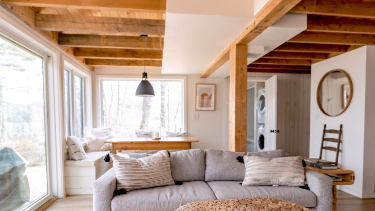 Jasny salon boho z drewnem, beżową sofą i naturalnym dywanem