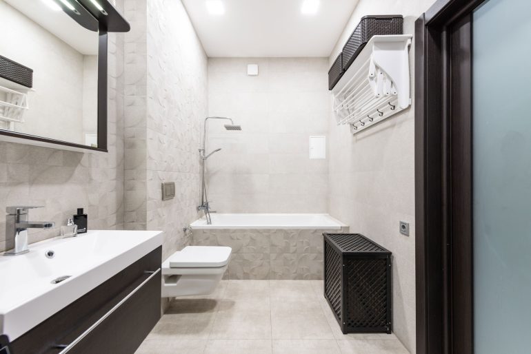 Kosz na pranie w małej łazience przy pralce i WC